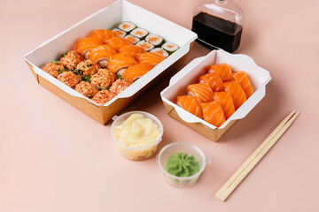 Set of sushi rolls with salmon in eco kraft paper containers on pink background. Food delivery concept. Sushi rolls take away in box.
