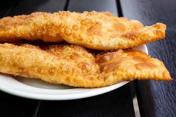 Pasties baked in preheated oil. meat-stuffed pies baked in hot oil on a white plate, close-up.