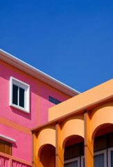 Manipulation techniques for architectural background design of colorful colonnade orange house with pink building against blue clear sky in perspective side view and vertical frame