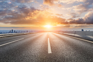 Empty asphalt road with modern city skyline and buildings at sunrise © ABCDstock