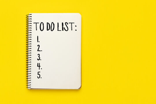 Open spiral notebook with to do list on bright yellow background with copy space, top view, flat lay