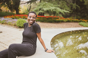 Attractive happy smiling young natural beauty short haired African woman wearing total black...