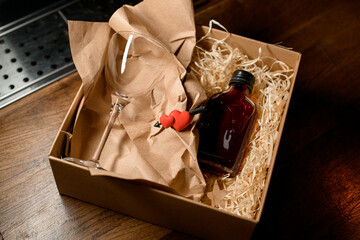cardboard box with glass and a small bottle with drink and a decorative heart