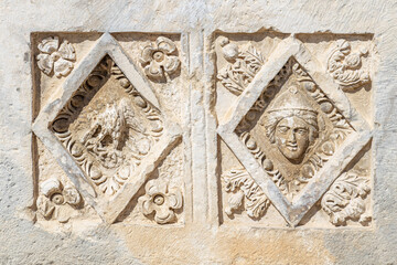 Ancient greek stone carvings in the yellow limestone rock. Facade of the building decoration in antique style
