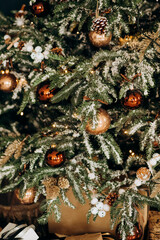 Christmas tree with shiny baubles in living room. Branches of Christmas trees with golds and brown toys and garland. Winter holidays.