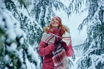 Beautiful smiling young woman in warm clothing outdoors in snowy park