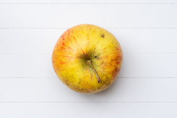 Ein Apfel auf einem weißen Holzbrettchen