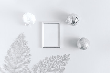 Minimal aesthetic christmas composition, silver shiny decorations on white background. Flat lay, top view.