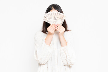 白い背景の前に立って、お金を見せる主婦
