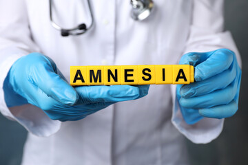 Doctor holding yellow cubes with word Amnesia, closeup