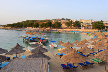 Beach with sun beds and umbrellas at sunset in Ksamil, Albania