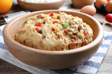 Raw dough with candied fruits and nuts for Stollen in bowl on wooden table, closeup. Baking traditional German Christmas bread