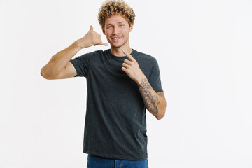 Young blonde man pointing finger away and making call gesture