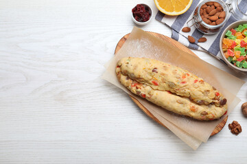 Unbaked Stollen with candied fruits and raisins on white wooden table, flat lay. Space for text