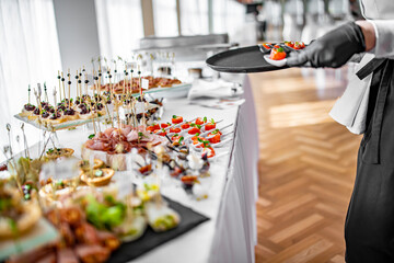 woman hands of a waiter prepare food for a buffet table in a restaurant