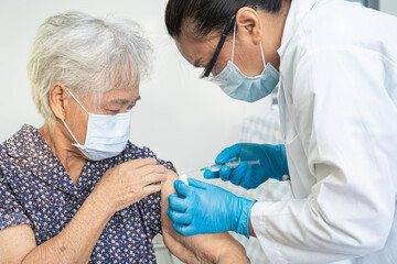 Elderly Asian senior woman wearing face mask getting covid-19 or coronavirus vaccine by doctor make...