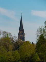 The tower of the parish church St.Matthias behind green trees