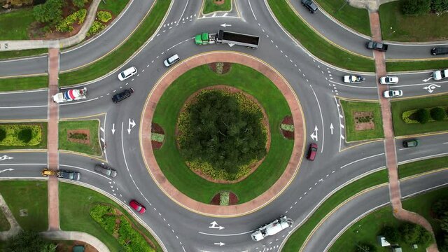 Aerial view of a roundabout with traffic circling. Top down drone shot with slow zoom in.