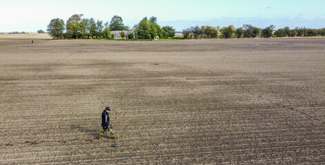 Detectorist searcing on newly sown land