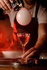 Male hand holds wineglass with beverage decorated with hearts and make smoky air bubble by flavour blaster