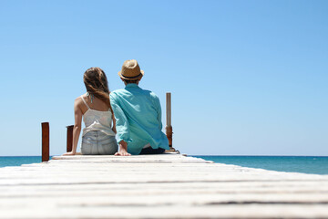 romantic couple sitting together in front of the sea