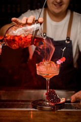 beautiful view of the crystal wine glass in which steaming cocktail is poured from mixing cup