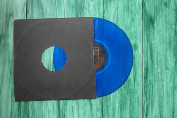 Aged black paper cover and blue vinyl LP record isolated on green background	