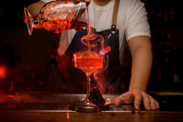 great view of the crystal wine glass in which steaming cocktail is poured from mixing cup
