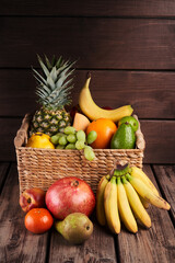 Mix of fresh juicy colorful exotic tropical fruits in basket on wooden background