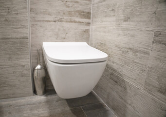 White wall-hung toilet. gray tiles, bathroom