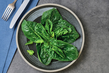 Idea of spinach leaf salad on a plate, top view. Nearby are cutlery. Spinach is an organic healthy...