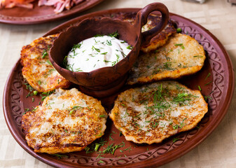 potato pancakes with sour cream and herbs on white plate
