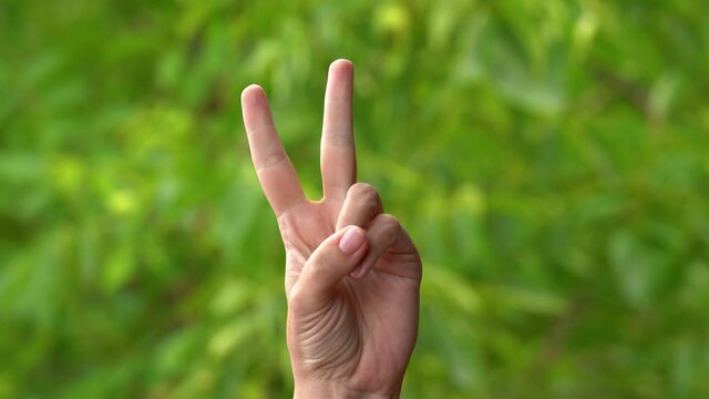 Woman showing different gestures with her fingers isolated on green nature bokeh background. V victory sign, rock, horn, okey, thumb up, like, offensive signs