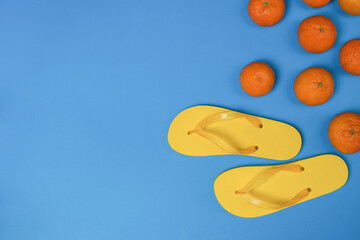 Tangerines and yellow beach slippers on a blue or purple background. Natural fresh organic fruits. Healthy food, raw food diet. Drive. Poster. 
