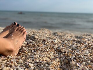 Female feet on the background of the blue sea.