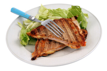 Croque-monsieur coupé en deux servi dans une assiette avec de la salade et une fourchette sur fond blanc