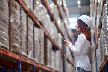 Woman sideways to camera with tablet looking at warehouse shelves