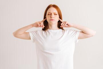 Portrait of frustrated young woman covering her ears and gesticulating say no bla-bla-bla standing...
