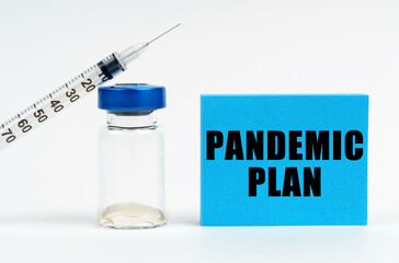 On the table is a syringe, an injection and a blue sign with the inscription - PANDEMIC PLAN