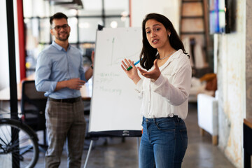 Businesswoman present her idea to working team. Young beautiful woman presenting businessplan..