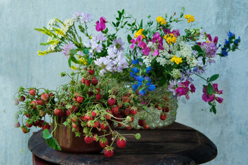 wildflowers bouquet and wild strawberry at stucco wall, rustic still life