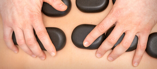 Hot stone massage therapy. Caucasian young man getting a hot stone massage on back at spa salon