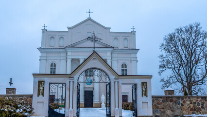 The Church of saints Cosmas and Damian in Ostrovets Grodno region with branch of tree on grey sky background.