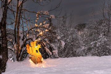 A lighted wooden angel on a snowy mountain forest. Christmas atmosphere on the Julian Alps,...