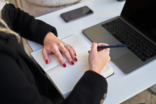 Anonymous freelancer woman writing notes while working with laptop in cafe - Powered by Adobe