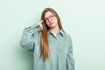 caucasian red hair woman with a concentrated look, wondering with a doubtful expression, looking up...