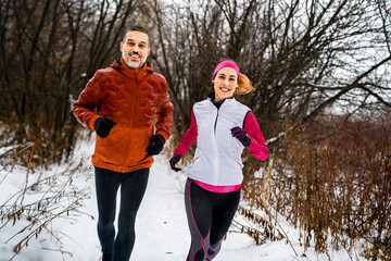 Runner couple jogging in park in warm winter sports clothing