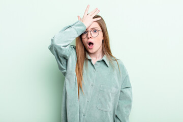 caucasian red hair woman raising palm to forehead thinking oops, after making a stupid mistake or...