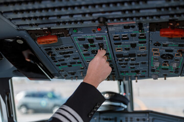 Aircraft pilot operating overhead panel of airplane flight deck