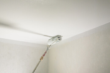 painting a white ceiling in a room with a roller